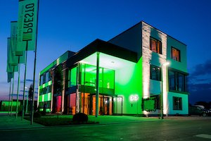 Aussenaufnahme von grün angestrahltem Presto-Bürogebäude bei Nacht